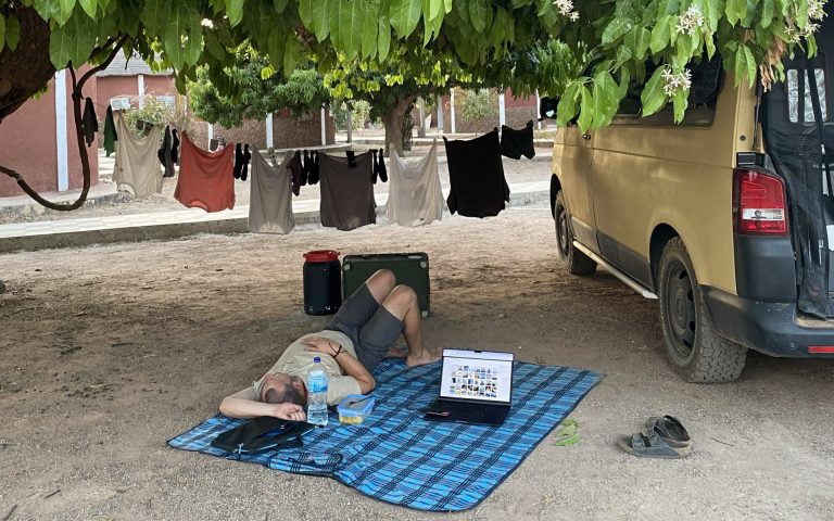 a marcel lying on a blanket under a tree with a laptop